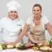 Two female chefs with variety of fresh ingredients in a kitchen setting, showcasing culinary preparation.