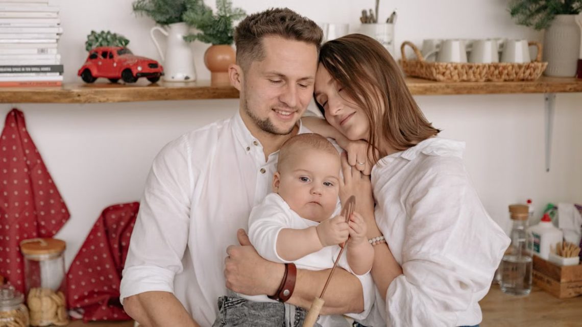 A joyful family of three embracing in a cozy kitchen. Warm and loving atmosphere.