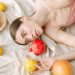 A serene woman in pink lies among vibrant citrus fruits on a soft linen cloth.